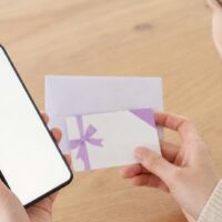 ホットペッパービューティーのギフト券がいつ届くかを確認するスマートフォンとギフトカードのイメージ