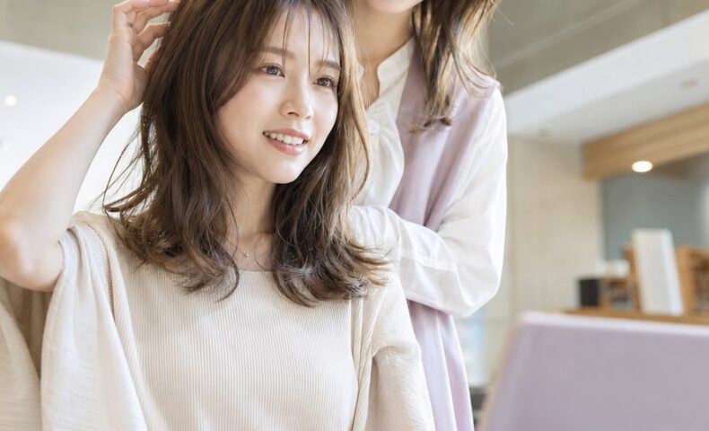 美容院レビューの例文を紹介する記事のアイキャッチ画像。ヘアサロンで仕上がりを確認する女性とレビュー入力をイメージした場面