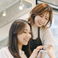 美容室の良い口コミ例文を考える女性とヘアサロンの店内