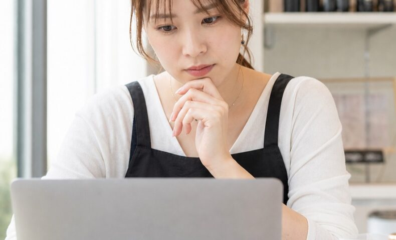 ネイルサロン SEO対策を進めるため、ノートパソコンで検索結果や予約導線を確認するネイルサロン運営者