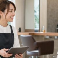 サロン集客支援のメリットをイメージした、スタッフと顧客が笑顔で相談する美容サロンの店内