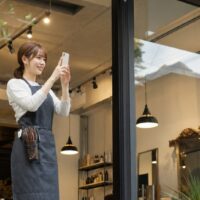 サロンのスタッフがスマートフォンでストーリーを発信し、予約につながる集客効果を高めるイメージ