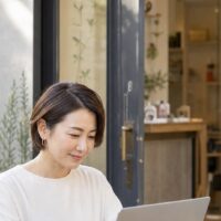 サロン集客 ChatGPT 活用をイメージした、ノートパソコンで集客アイデアを考える美容サロン経営者